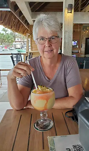 Photo of Vice President Donna Stokell with a frosty fruity cocktail during a tropical vacation